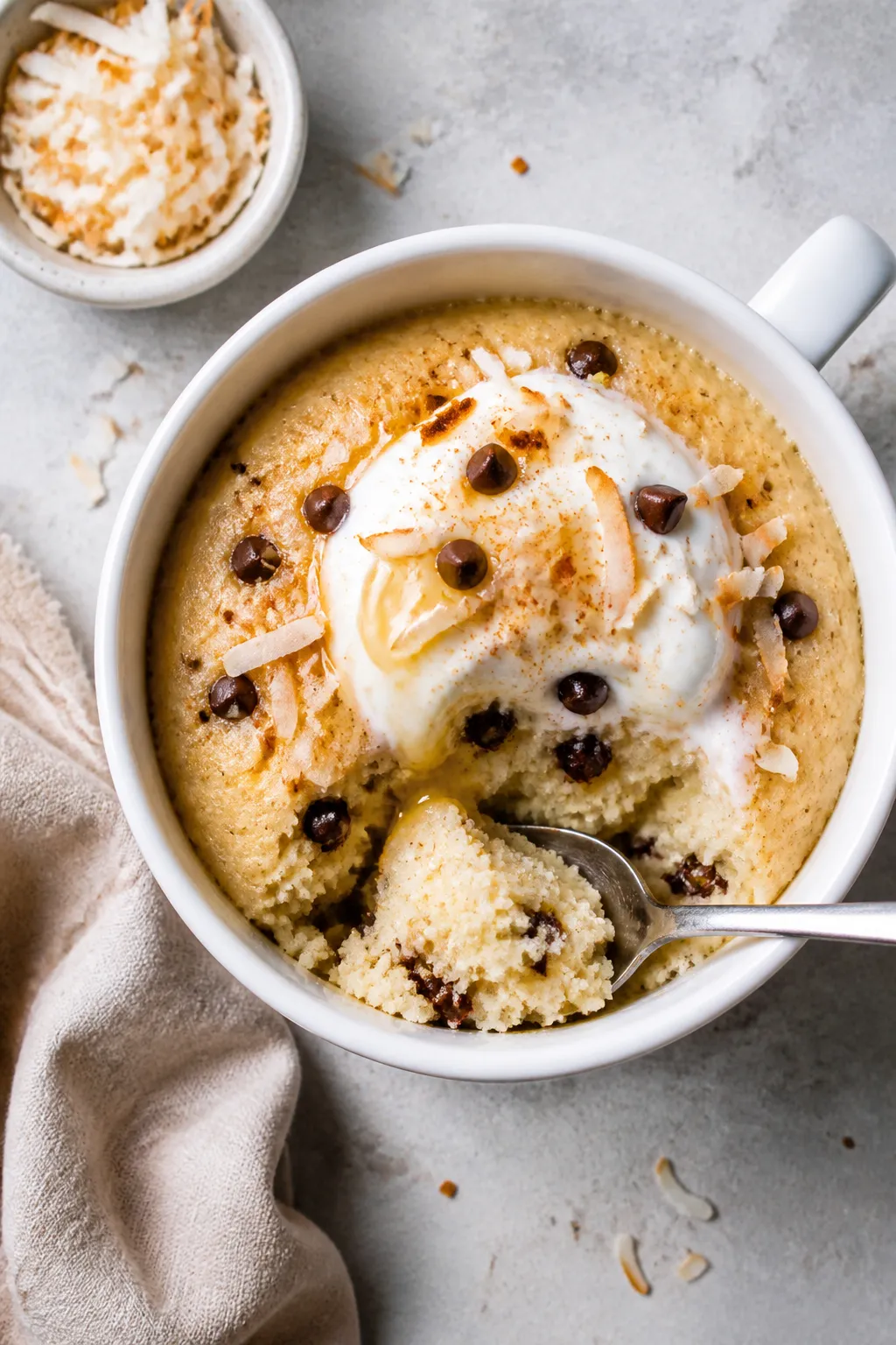 Final plated, overhead hero: Fully cooked Vanilla Coconut Cottage Cheese Mug Cake served in a white