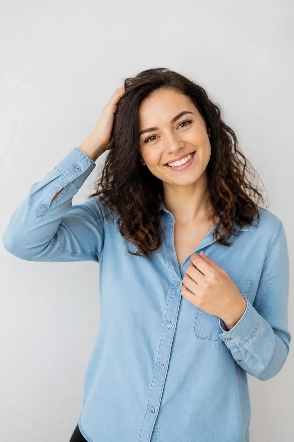 Candid professional photograph of a genuine real human model with lifelike skin and a natural expression. PG-rated, family-safe, modest editorial stock photograph. Any visible person is fully dressed in normal everyday clothing before anything else: shirt or top on, shoulders covered, chest covered, torso covered, waist covered, legs modestly covered, relaxed natural pose. Half- subtle shine, clean backdrop, hands visible arranging hair for a candid feel, natural light,. complete face and entire head comfortably inside the frame, clearly visible, sharp and in focus, generous headroom, unobstructed face, bright expressive eyes, natural warm smile, lively alert expression. genuine real human model in a candid professional photograph, lifelike warm skin texture, real pores, natural human expression, realistic body proportions. single natural human body with believable ordinary posture, arms naturally attached to the shoulders, no extra arms, no extra hands, no floating hands, no disembodied limbs, no duplicate face, no cloned body parts, no warped fingers, no impossible pose. wholesome family-friendly safe-for-work image. If any human appears, use tasteful modest everyday clothing with upper body, shoulders, chest, torso, waist and legs covered, natural simple relatable styling, calm neutral mood, appropriate for a general audience. high quality photorealistic image, sharp focus, natural true-to-life colors, coherent realistic anatomy, exactly two arms per visible person, exactly two hands per visible person, five fingers on each visible hand, one unique natural face per visible person, balanced facial symmetry, one clear main subject, uncluttered background, only props that directly match the topic and section Clean camera photo with plain unmarked real-world surfaces only &mdash; no text, no words, no letters, no numbers, no captions, no titles, no labels, no signs, no watermark, no logo, no poster typography, no handwriting, no subtitles, no UI. Only camera-captured realistic photography of real physical subjects in one uninterrupted natural scene, with authentic materials, natural depth, realistic lighting, coherent perspective and natural textures.